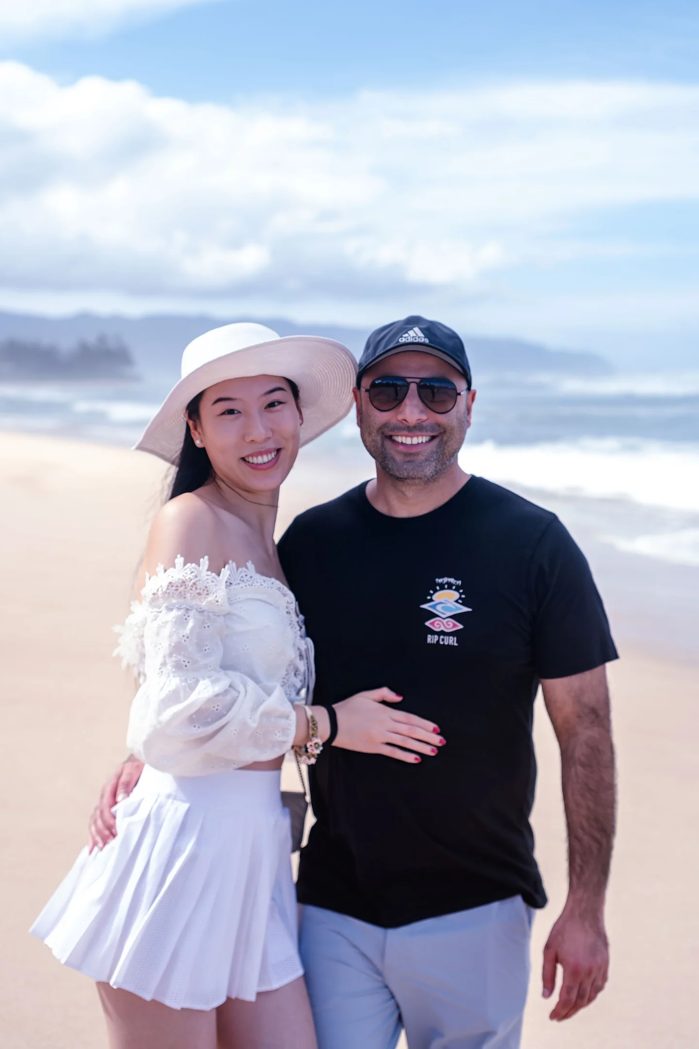 Smiling couple standing together on a sandy beach.