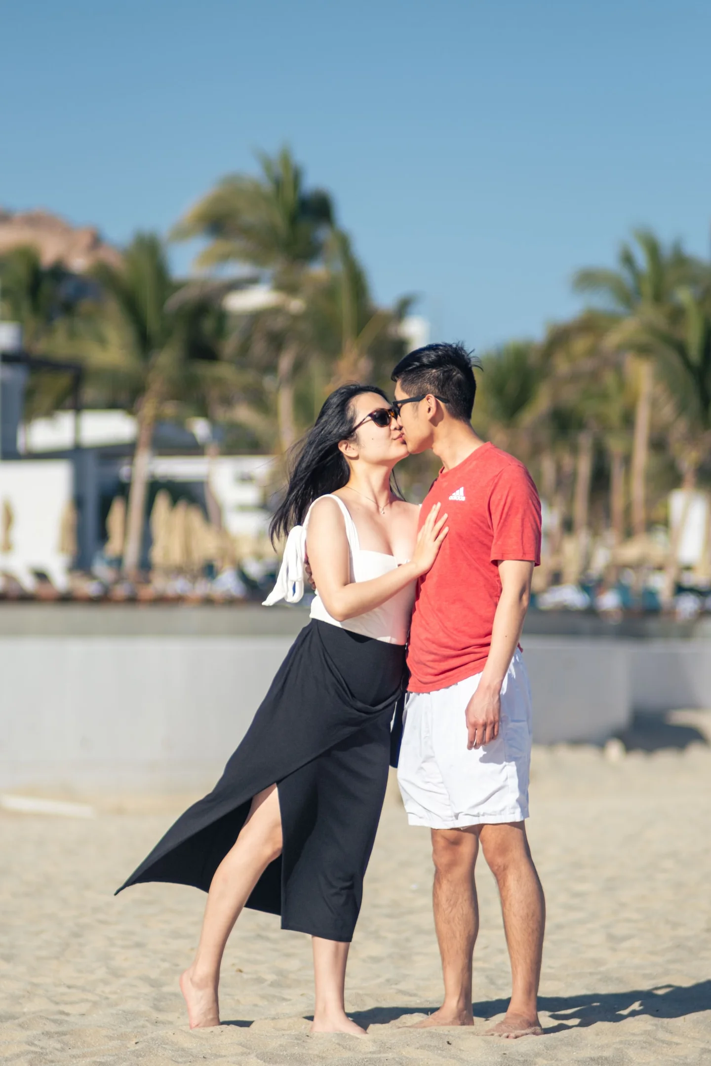 Couple kissing on a sandy beach.